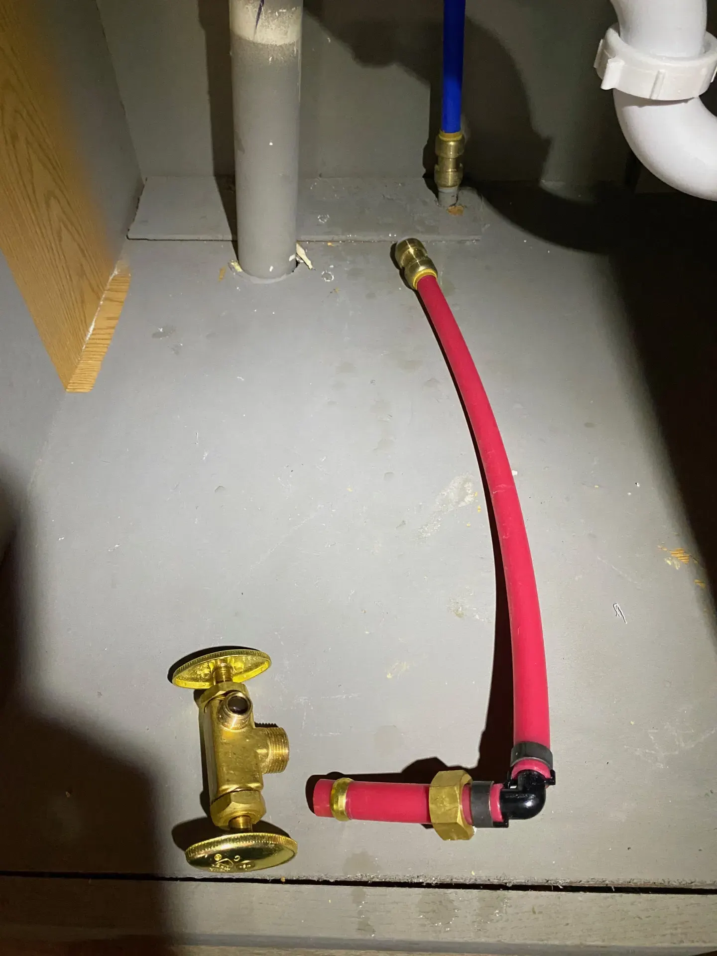 Red PEX supply line with push-to-connect, crimp ring, and compression fittings under a kitchen sink.