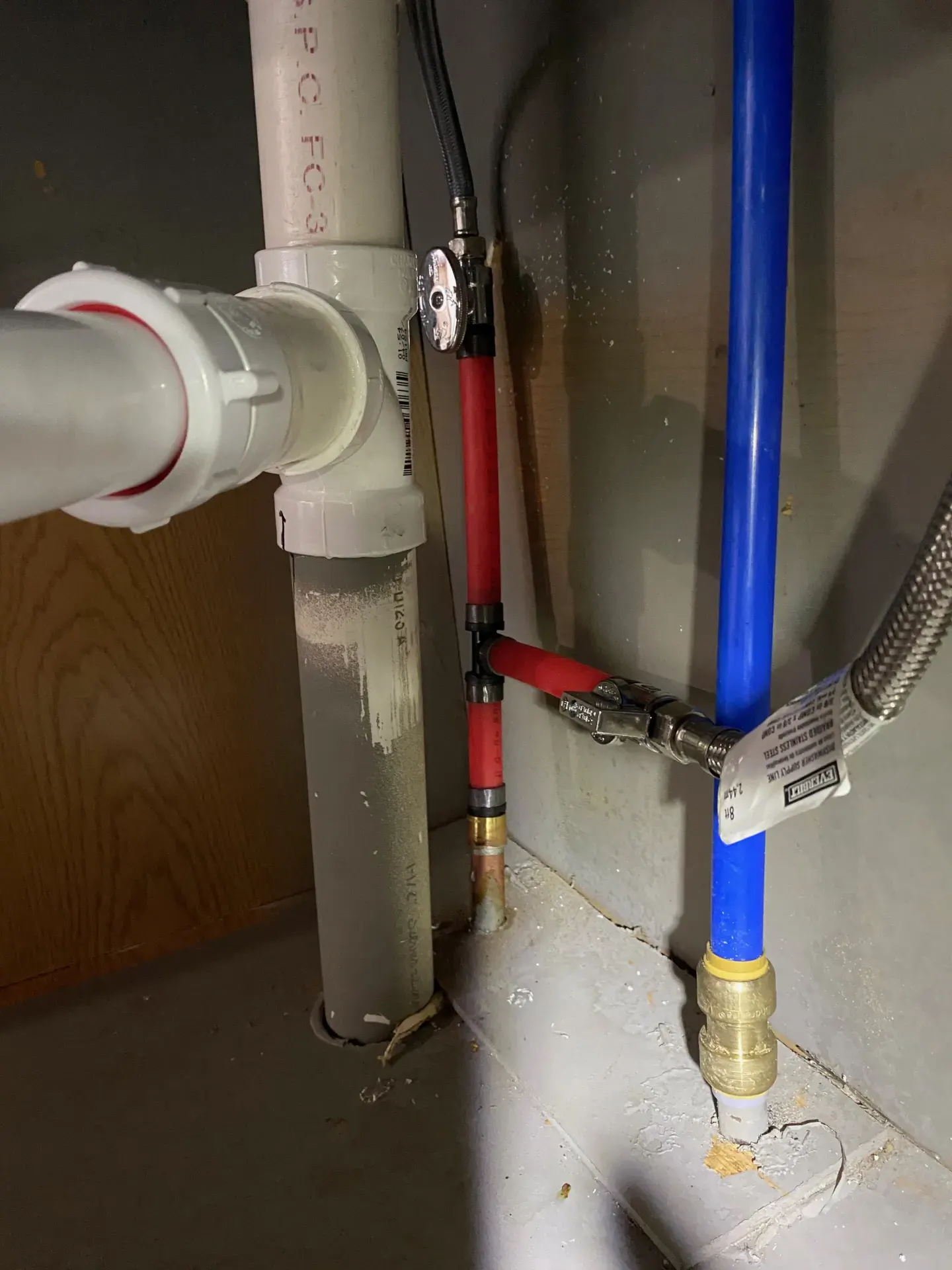 Repaired hot side supply line under a kitchen sink cabinet, reconnected with [soldered copper / crimped PEX] fittings.