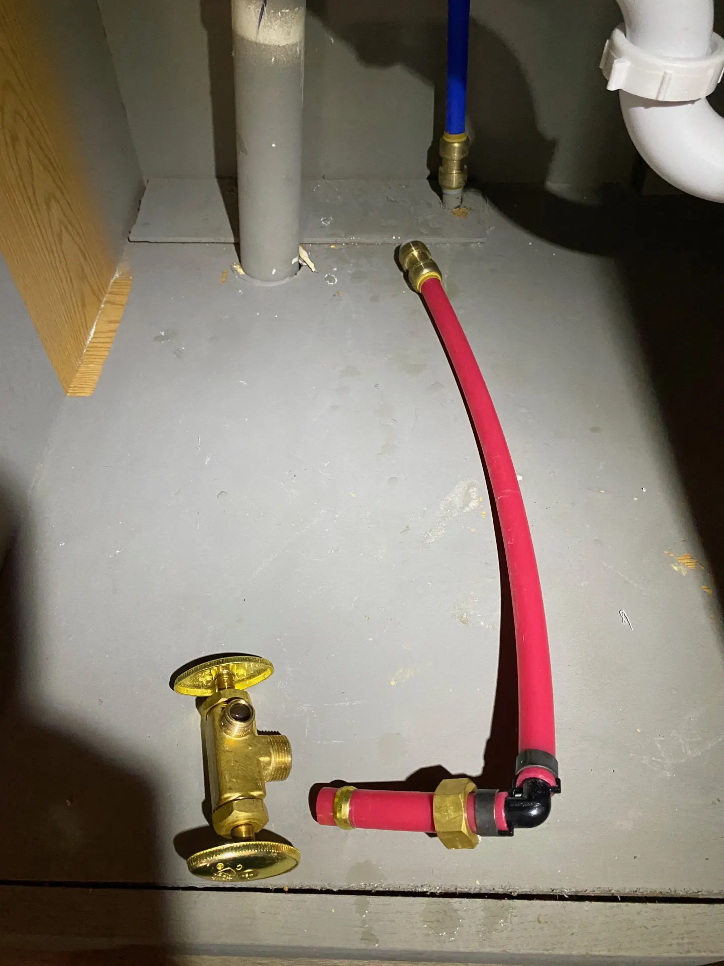 Red PEX supply line with push-to-connect, crimp ring, and compression fittings under a kitchen sink